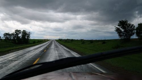 Road amidst trees seen through car windshield