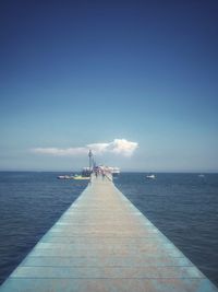 Pier over sea against blue sky