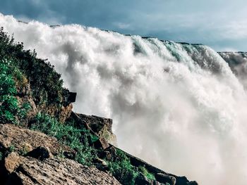 Low angle view of waterfall against sky