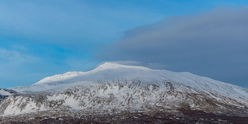 Panoramic view of snow capped mountain peak shrouded in clouds