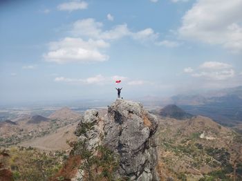 Man standing on rock by mountain against sky