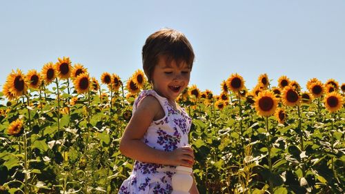 Girl standing on field against clear sky