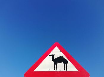 Low angle view of man standing against clear blue sky