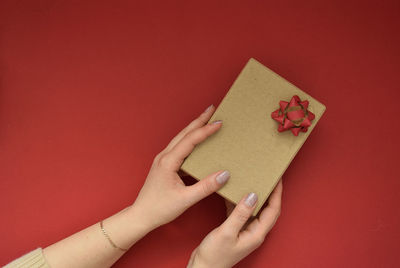 Cropped hands of woman holding gift against yellow background