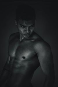 Portrait of shirtless man standing against gray background