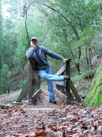 Portrait of man standing by tree in forest