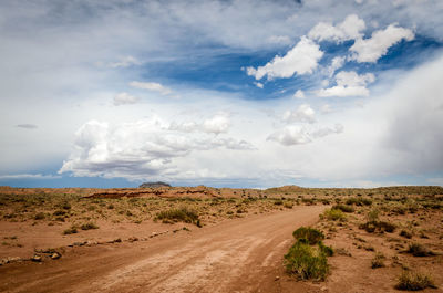 Dirt road amidst desert against sky