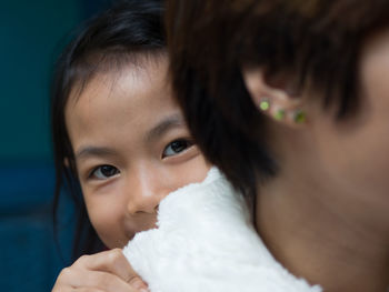 Close-up portrait of cute girl hiding behind mother