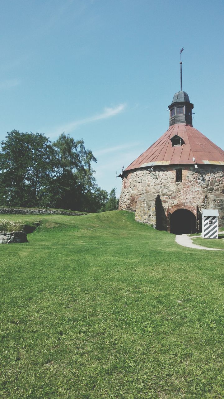 architecture, building exterior, built structure, grass, sky, tree, field, green color, religion, church, place of worship, blue, clear sky, low angle view, house, grassy, spirituality, tower, sunlight