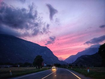 Road by mountains against sky at sunset