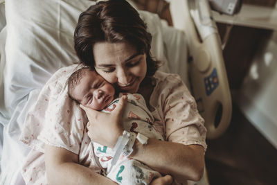 Mid view of mother in hospital bed looking at newborn son