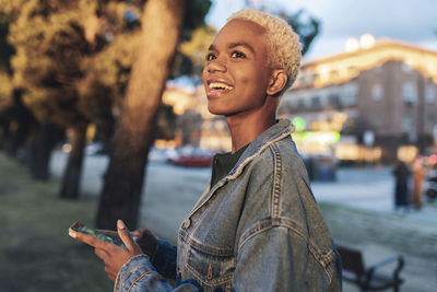 Happy woman in denim jacket holding smart phone