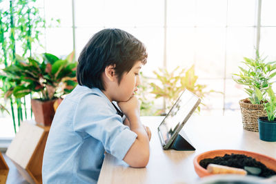 Side view of boy sitting on table at home