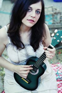 Portrait of young woman playing guitar