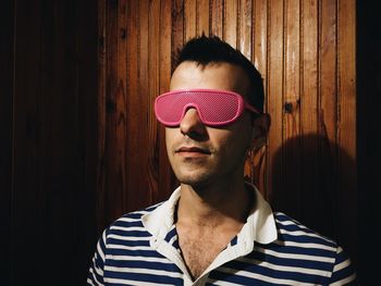 Young man wearing eyeglasses against wooden wall