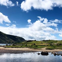 Scenic view of river by mountains against sky