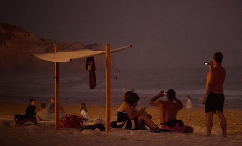 People at beach against sky during twilight