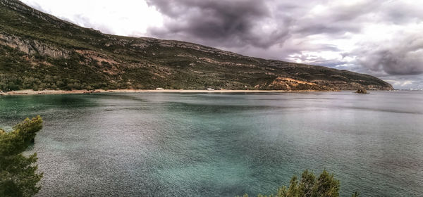 Scenic view of lake by mountain against sky