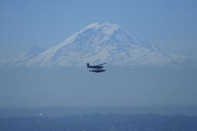 Airplane flying against snowcapped mountains in foggy weather