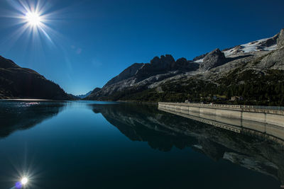 Scenic view of lake and mountains against blue sky