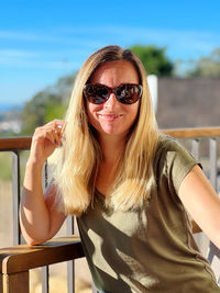 Portrait of young woman wearing sunglasses against sea