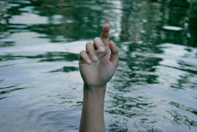 Close-up of hand holding water in lake