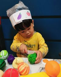 Boy cutting vegetables, toys on the table