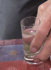 Midsection of man drinking glass on table