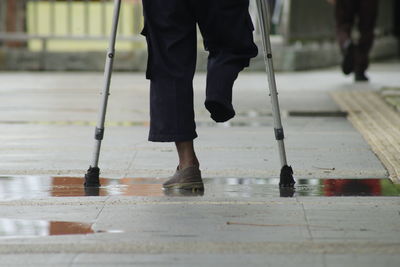 Low section of man standing on wet footpath