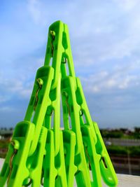 Close-up of green clothespins in triangle shape against sky