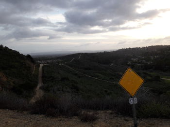 Road sign on landscape against sky