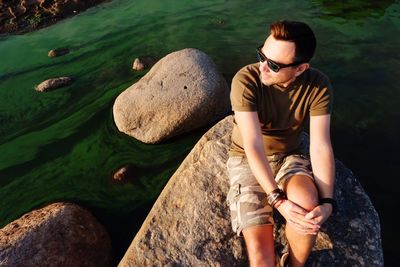 High angle view of young man sitting on rock