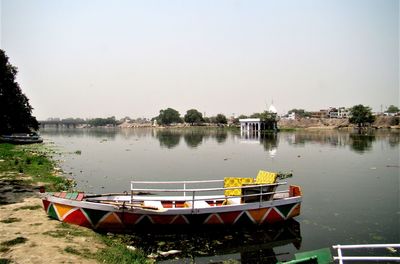 Boats moored in lake against clear sky