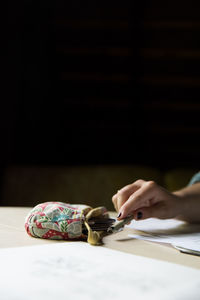 Cropped image of woman holding pen on table