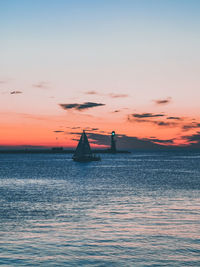 Silhouette boat sailing in sea against sky during sunset