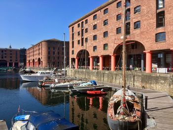 Sailboats moored on canal against buildings in city