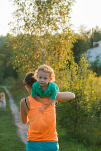 Full length of father and girl standing against trees