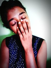 Close-up portrait of young woman against wall