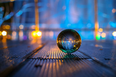 Close-up of crystal ball on table in illuminated city at night