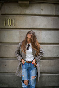 Full length of woman standing against wall