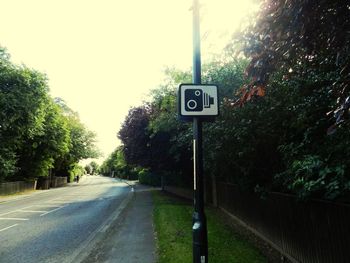 Road sign by street in city against sky