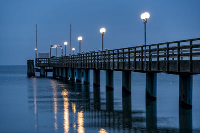 Pier over sea against clear sky at dusk