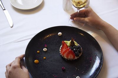 High angle view of hand holding strawberry in plate on table