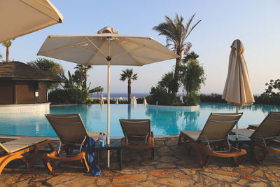 Lounge chairs by swimming pool against clear sky