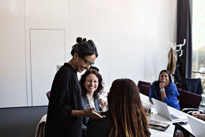 Smiling businesswoman talking to female colleagues sitting at conference table