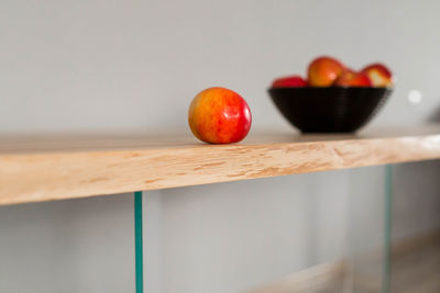 Close-up of apple on table against wall