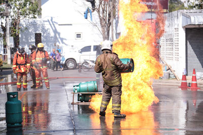 Firefighters standing on wet road against building