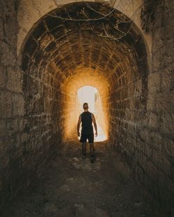 Full length rear view of man standing in tunnel