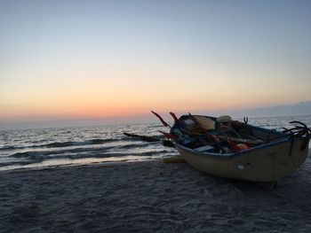 Boat moored on sea against sky during sunset