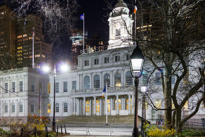 Illuminated street light by building in city at night